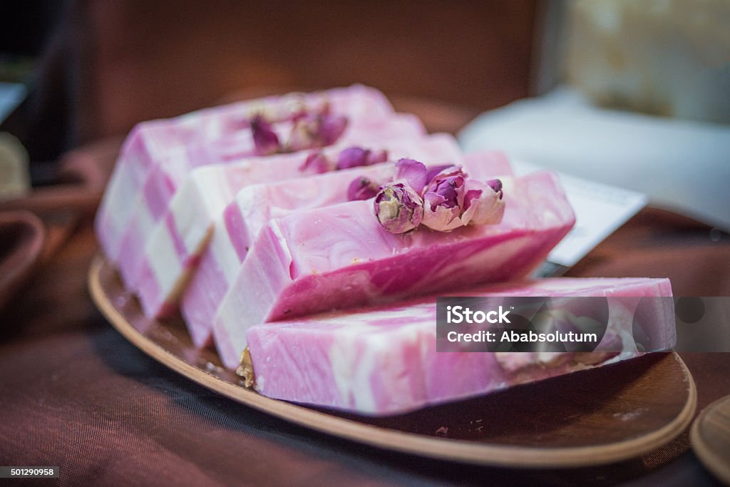 Rose soap bars in pink and white swirls on a wooden tray, top view
